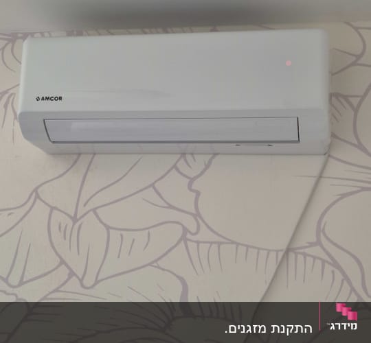 מזגן קיר לבן מותקן על קיר עם טפט פרחוני